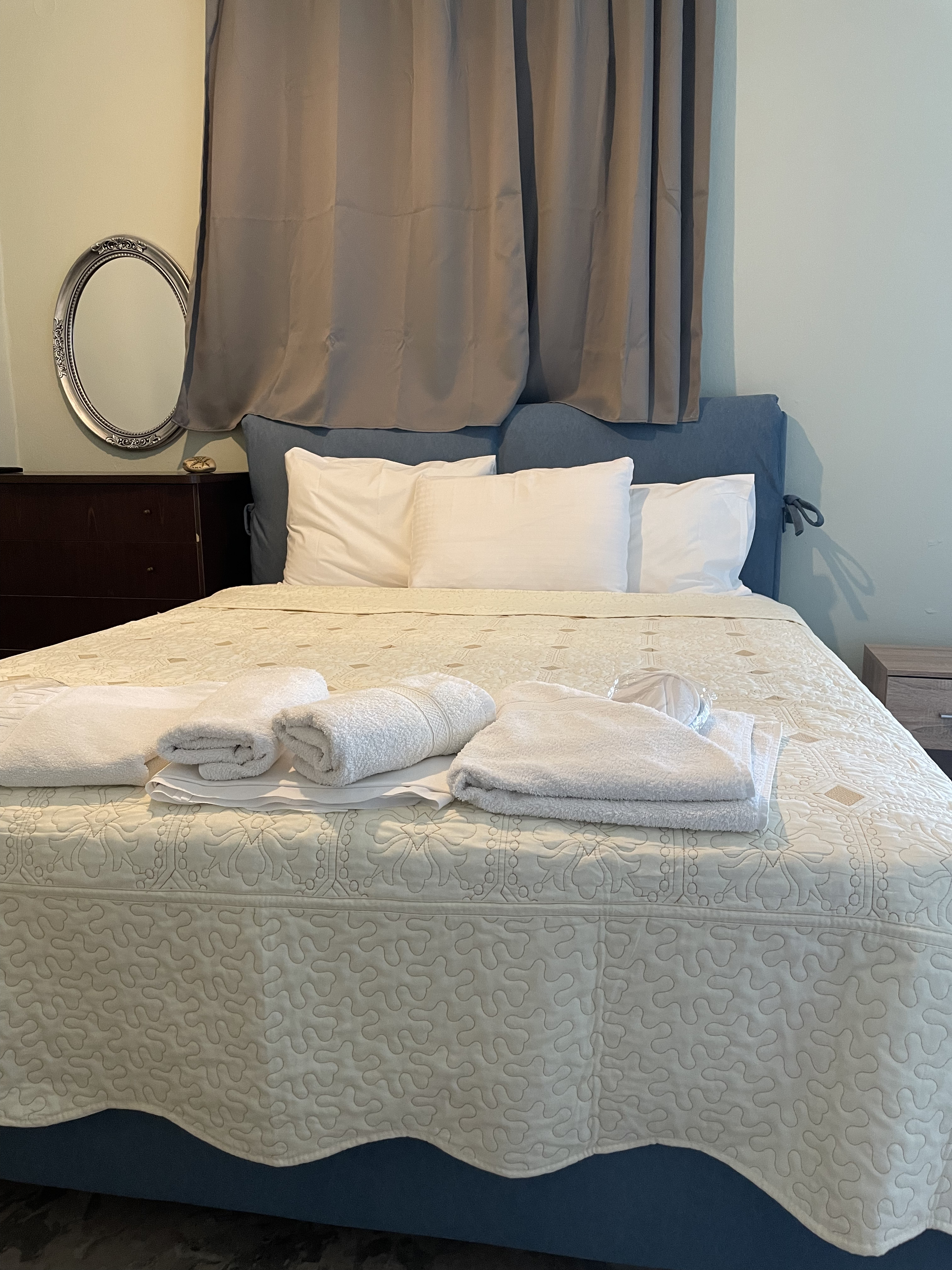 Double bedroom with white linen and oval mirror