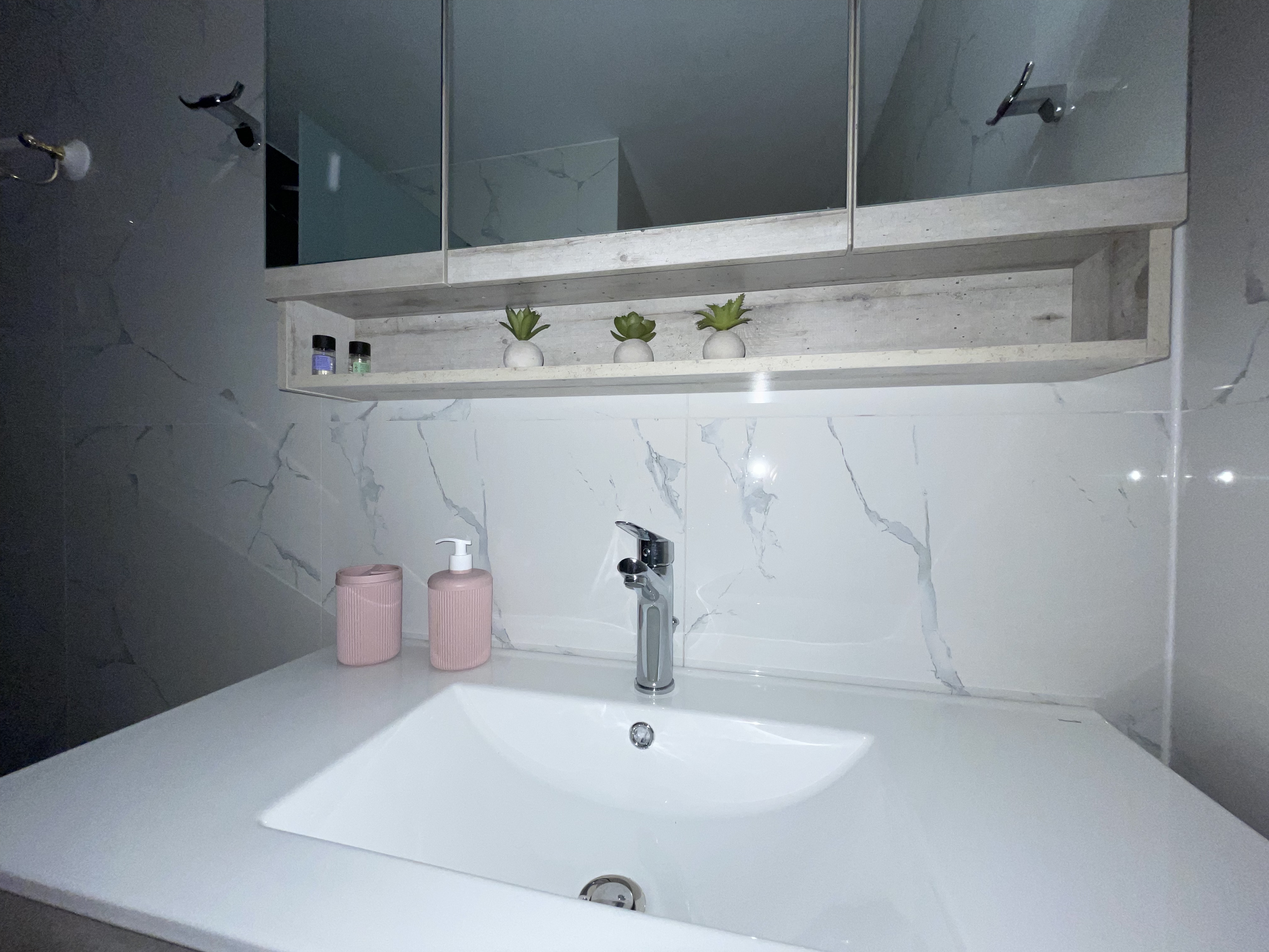 Bathroom sink with pink accessories and marble tiles